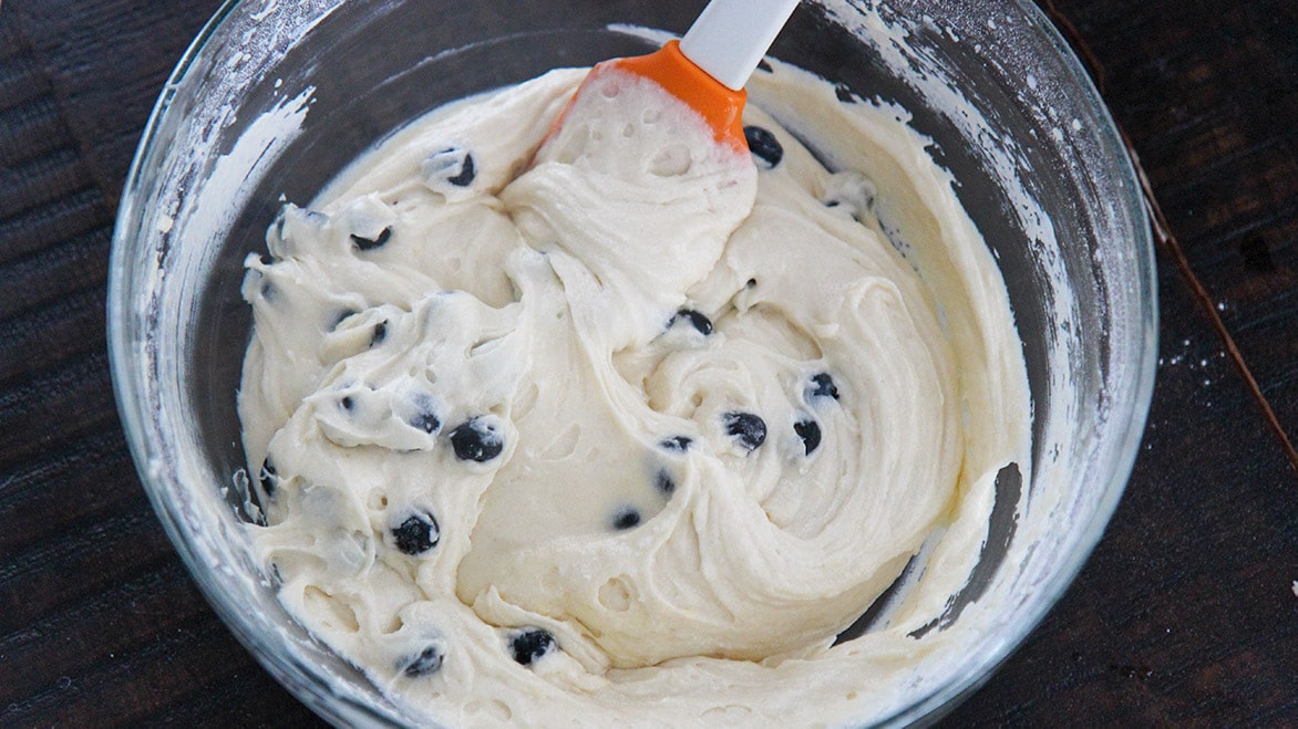 cake batter with fresh blueberries and a spatula 