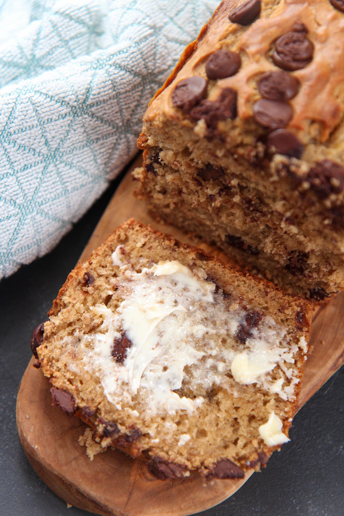 a slice of bread with butter smeared on top. A blue towel on the side. 