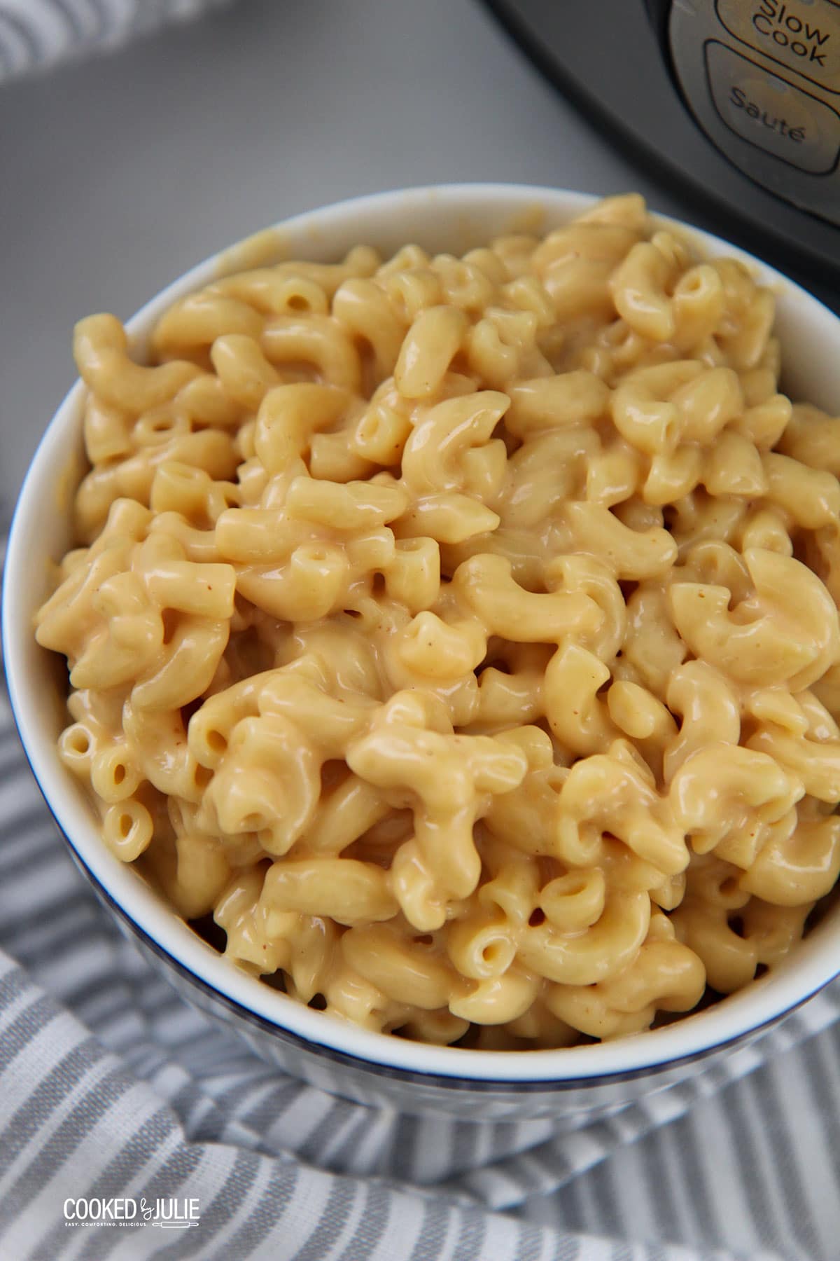 mac and cheese in a white bowl with a gray and white towel on the side. 