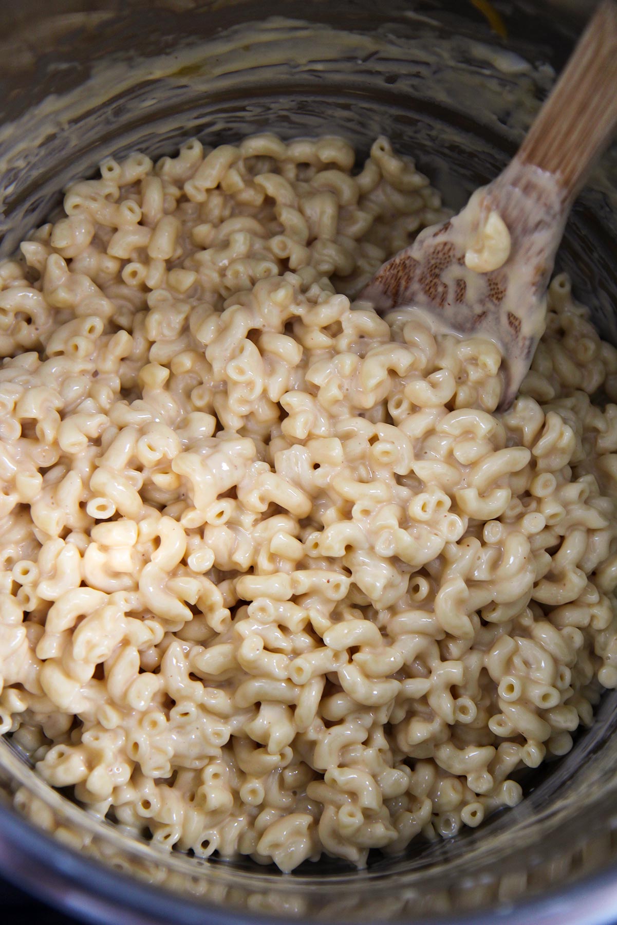 elbow macaroni and a wooden spoon inside a pressure cooker 