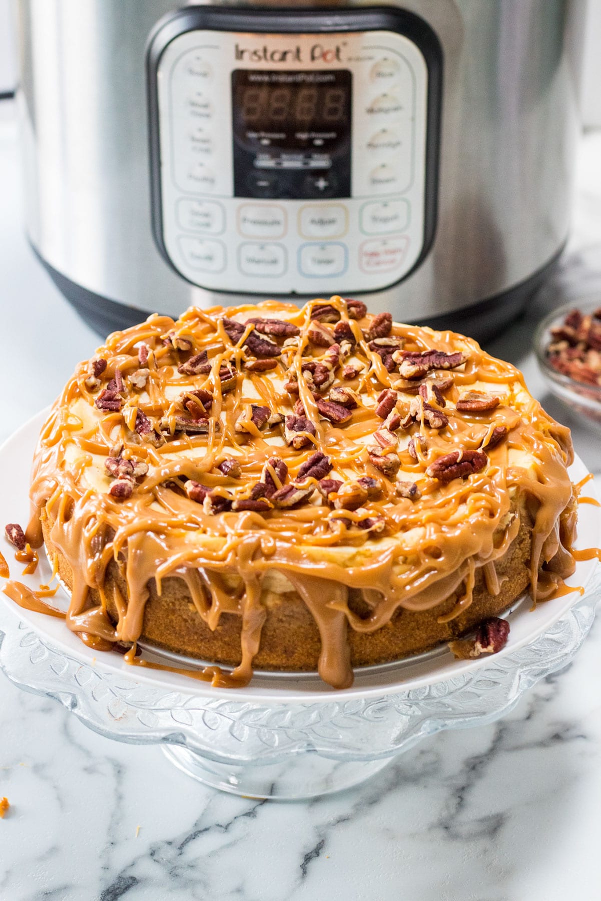 instant pot salted caramel cheesecake on a glass stand. 