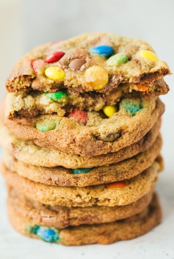 eight m&m cookies stacked on top of each other. One cookie is cut in half.