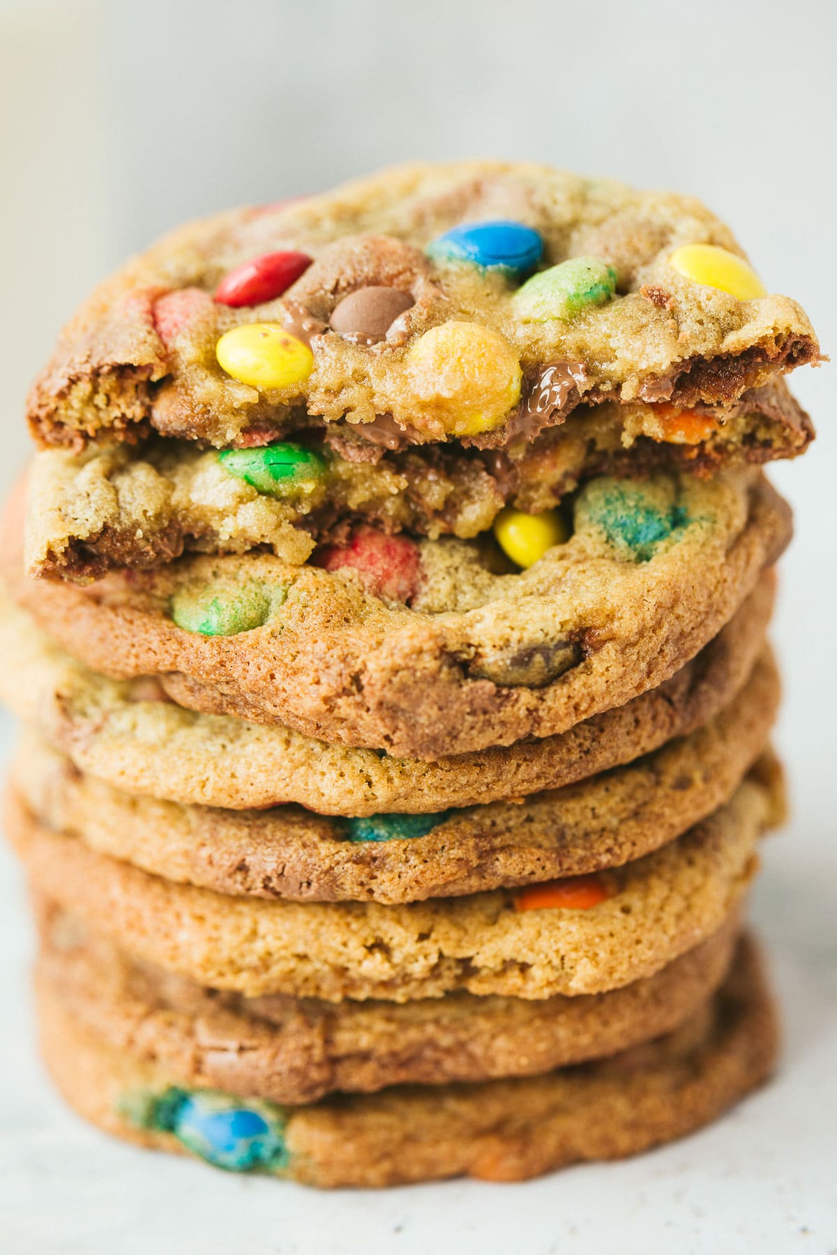 eight m&m cookies stacked on top of each other. One cookie is cut in half. 