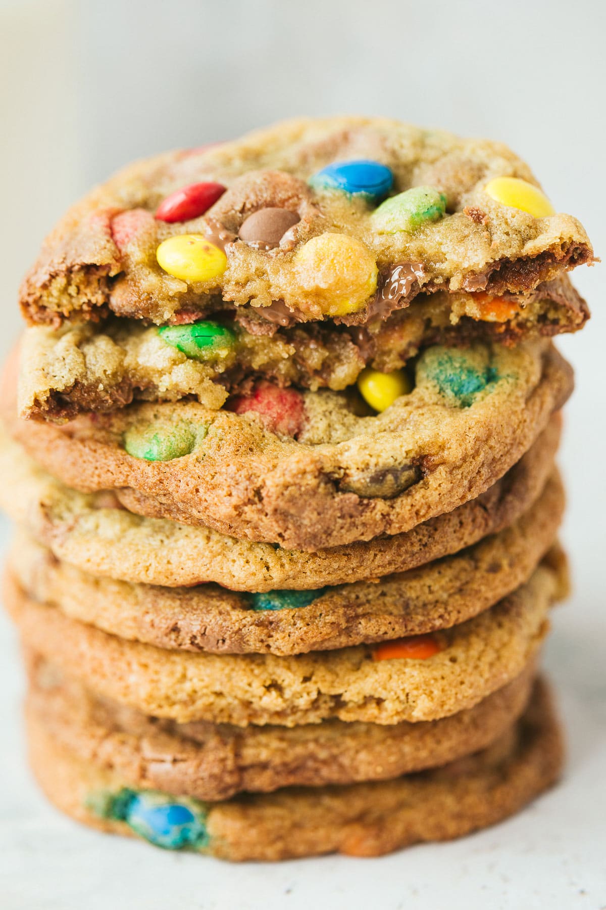 eight m&m cookies stacked on top of each other. One cookie is cut in half.