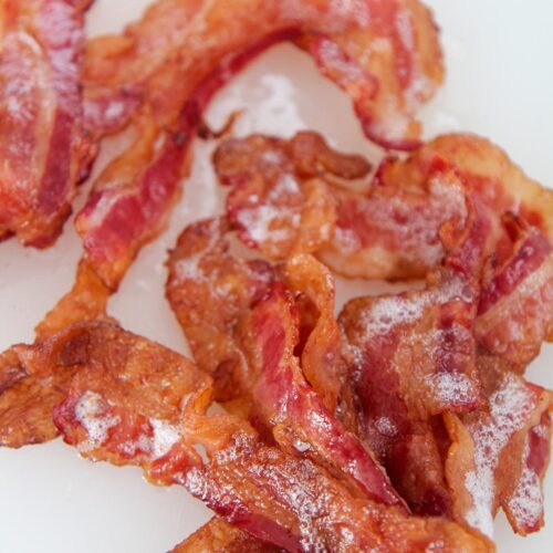 one pound of crispy bacon up close on a white chopping board.