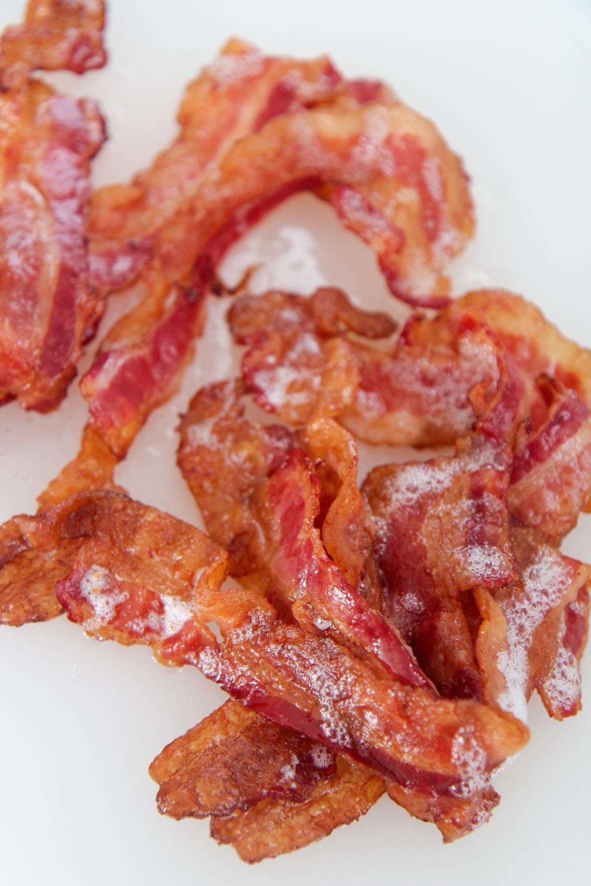 one pound of crispy bacon up close on a white chopping board.