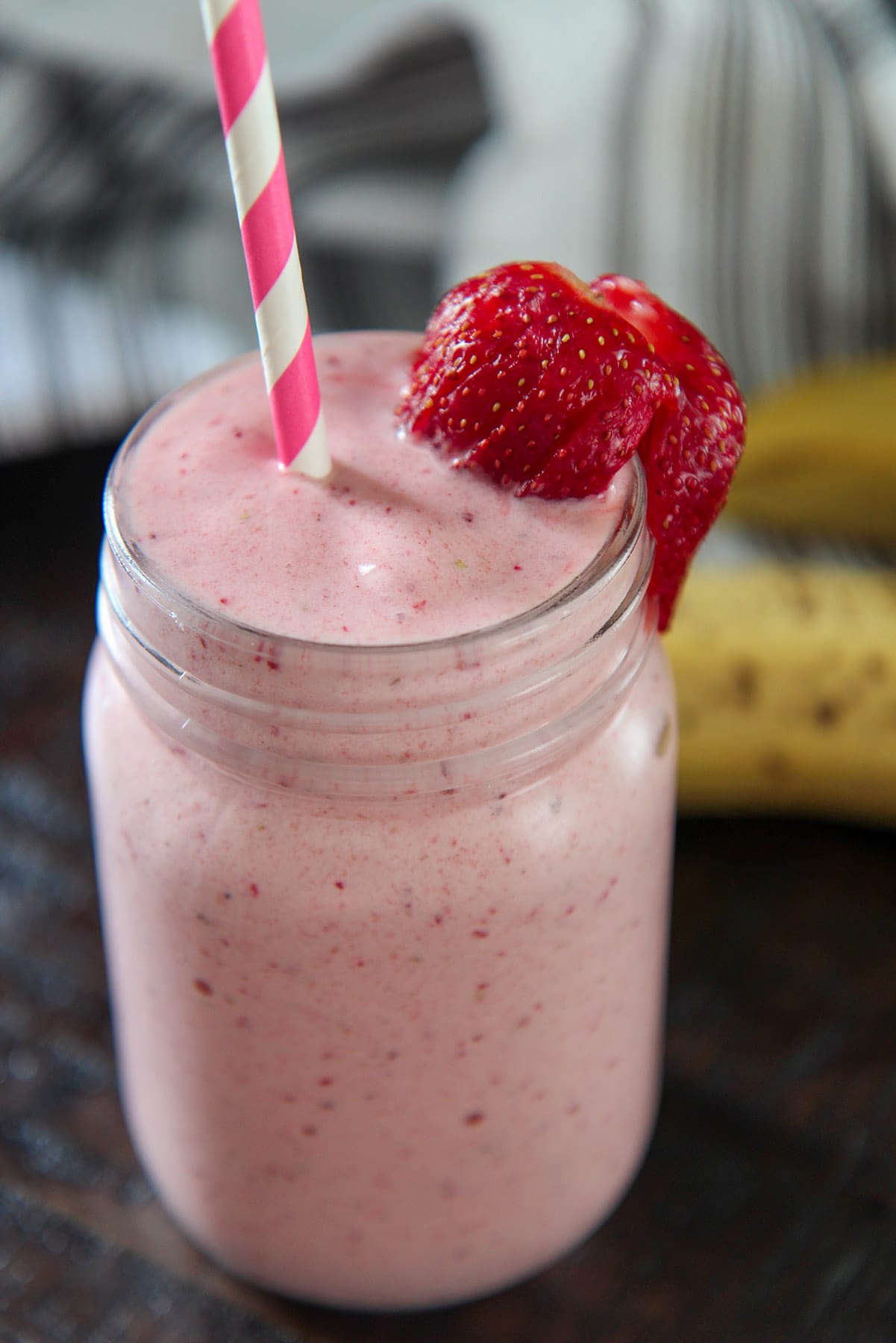 shake in a mason jar up close with a pink and white straw.