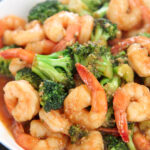 shrimp and broccoli with sauce in a white plate.