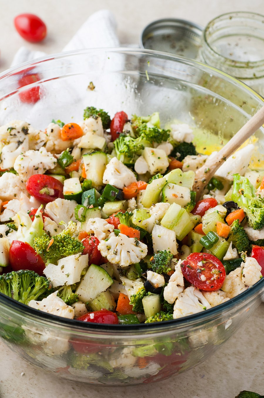 a bowl with colorful raw vegetables with a wooden spoon. 