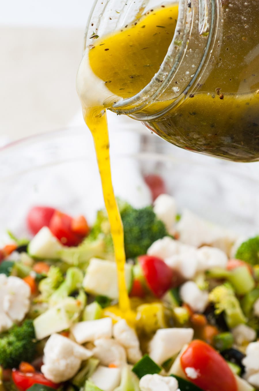 dressing poured over a bowl of vegetable salad.