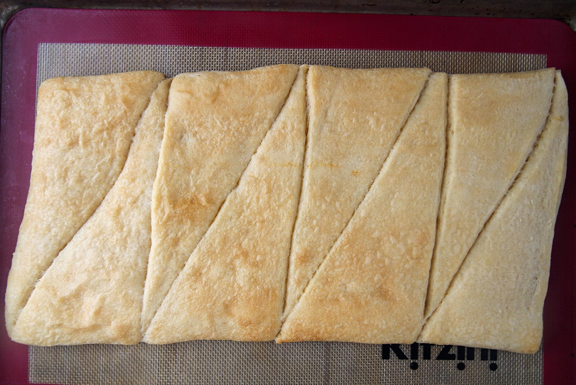 eight crescent rolls baked on a baking sheet.