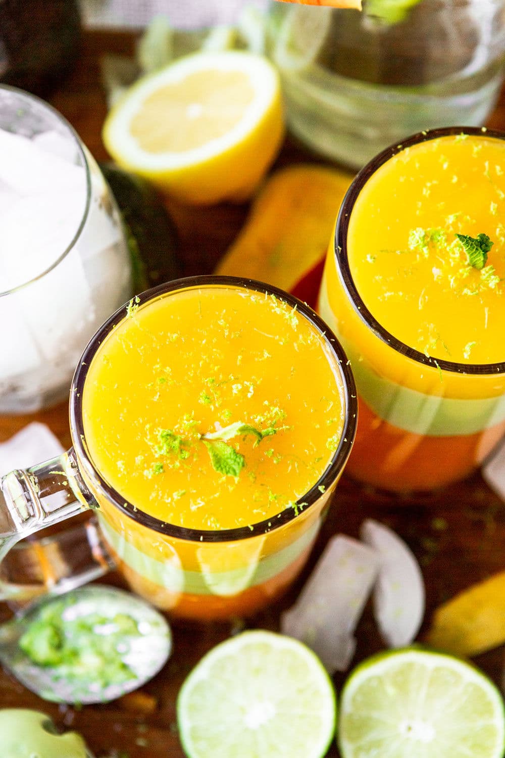 two tall glasses with yellow and green juice on a wooden board.