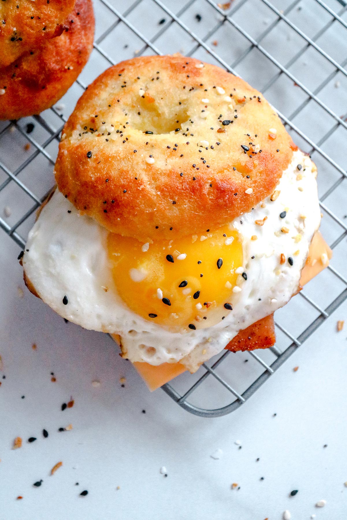 a keto breakfast sandwich with a sunny side up egg, everything bagel, and cheese on a wire rack. 