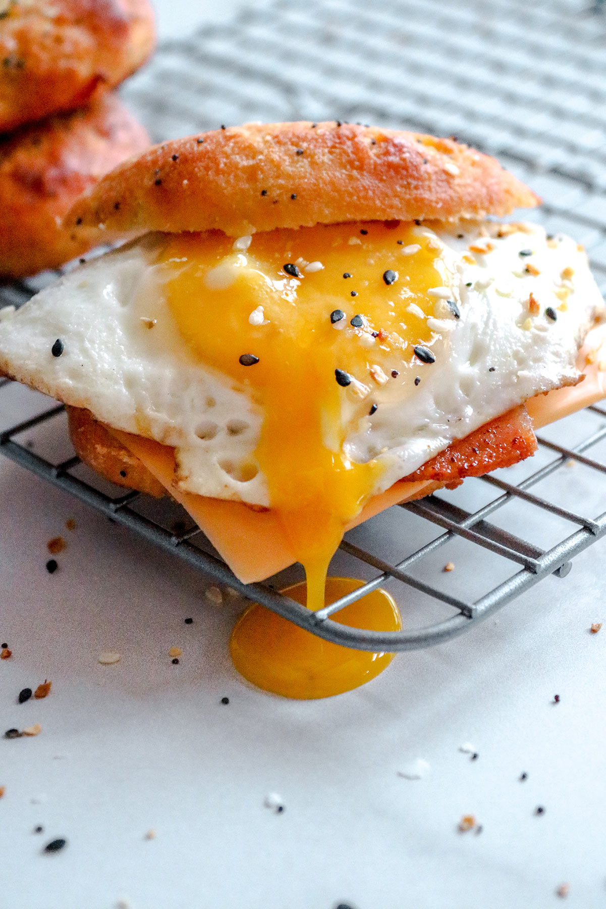 an up close shot of the keto breakfast sandwich with a runny egg on top of a wire rack. 