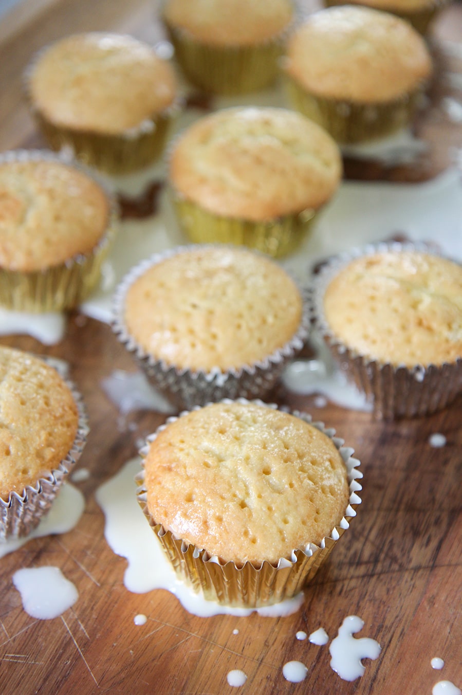 nine cupcakes with milk splattered on a wooden surface. 