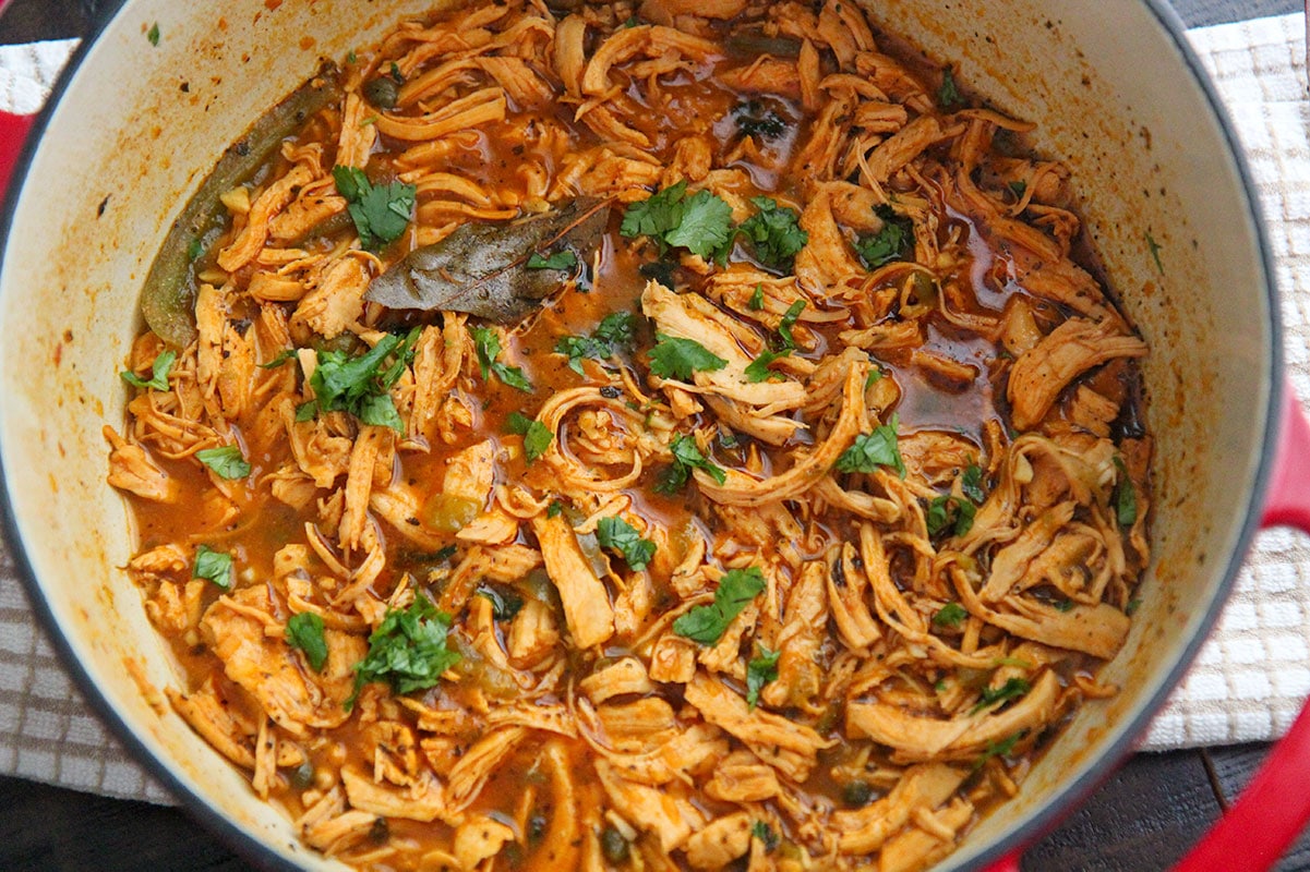 shredded chicken in sauce inside of a dutch oven. 