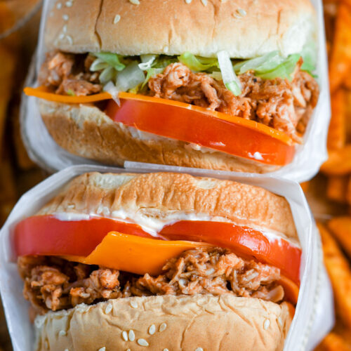 two chicken sandwiches stacked with sweet potato fries underneath.