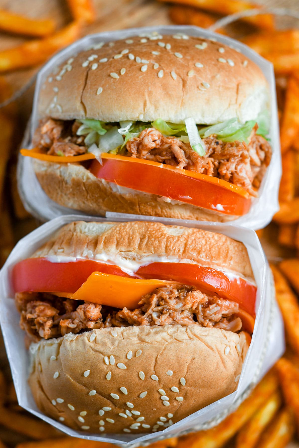 two chicken sandwiches stacked with sweet potato fries underneath. 