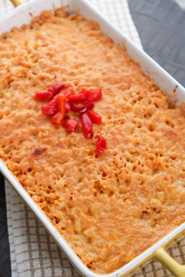 arroz imperial in a yellow casserole dish with melted yellow cheese and red peppers on the center.