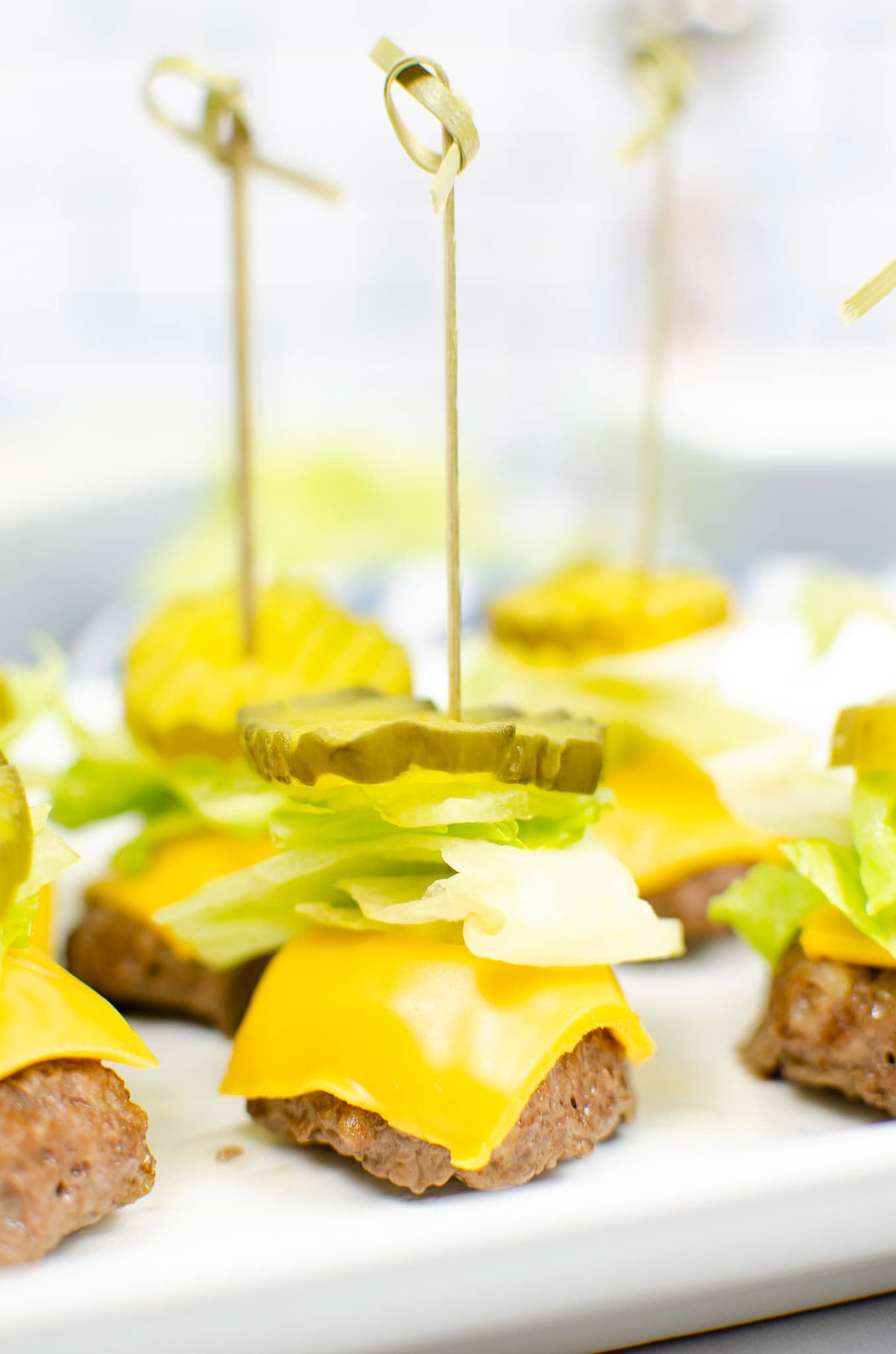 big mac bite with cheese, sauce, lettuce, pickle, and a toothpick up close. lettuce, 