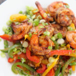 jerk shrimp with peppers and onions on a white plate.