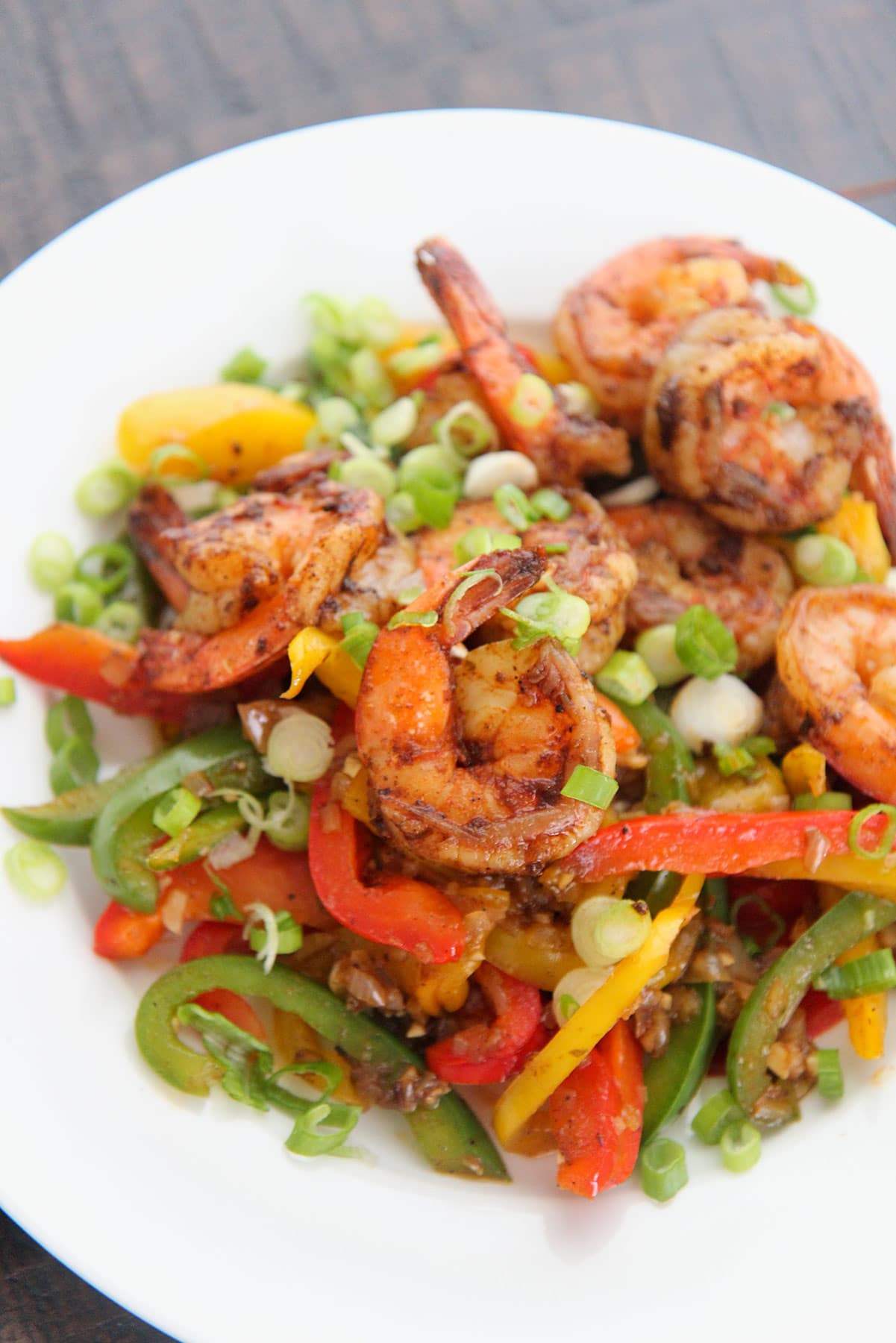 jerk shrimp with peppers and onions on a white plate. 