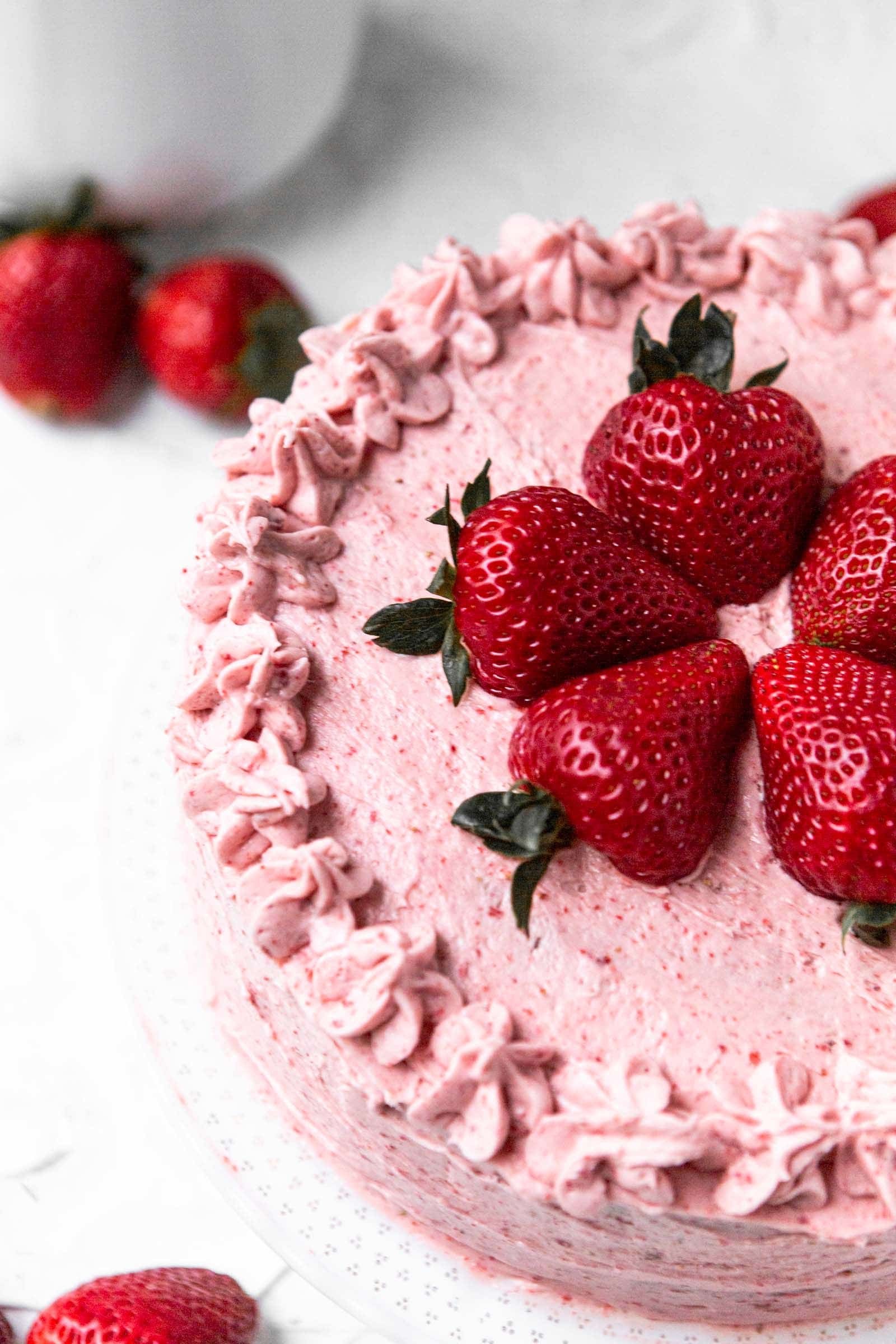 half of an entire strawberry cake with fresh strawberries on top and on the side. 