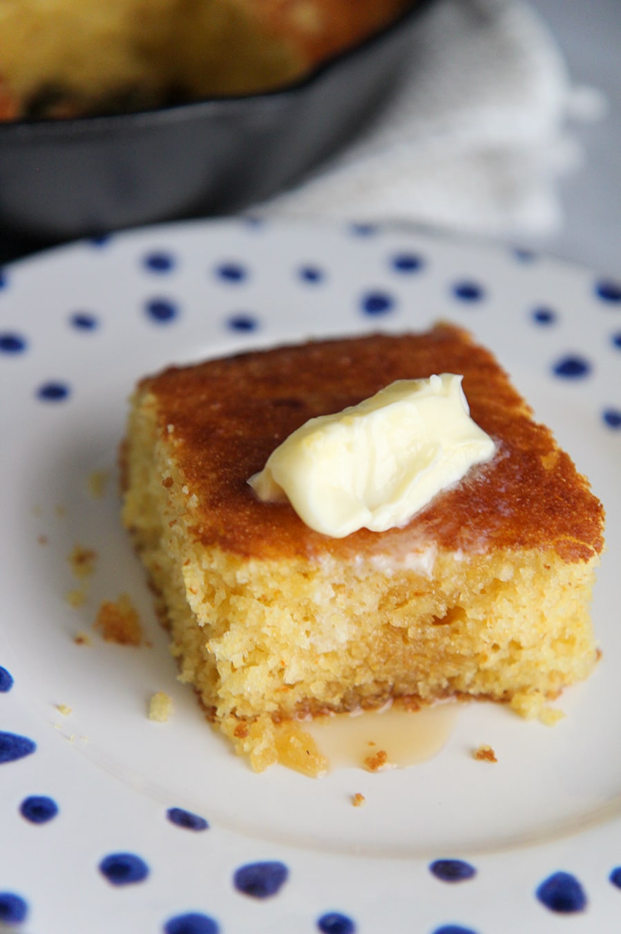 a slice of cornbread on a white plate with blue dots. 