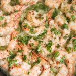 baked shrimp with parsley in a cast iron skillet up close.
