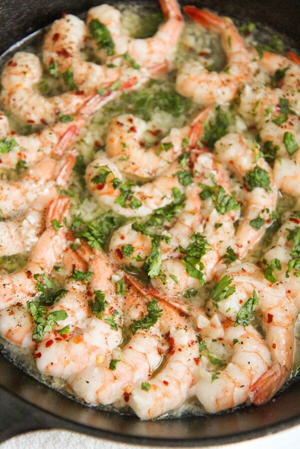 baked shrimp with parsley in a cast iron skillet up close.