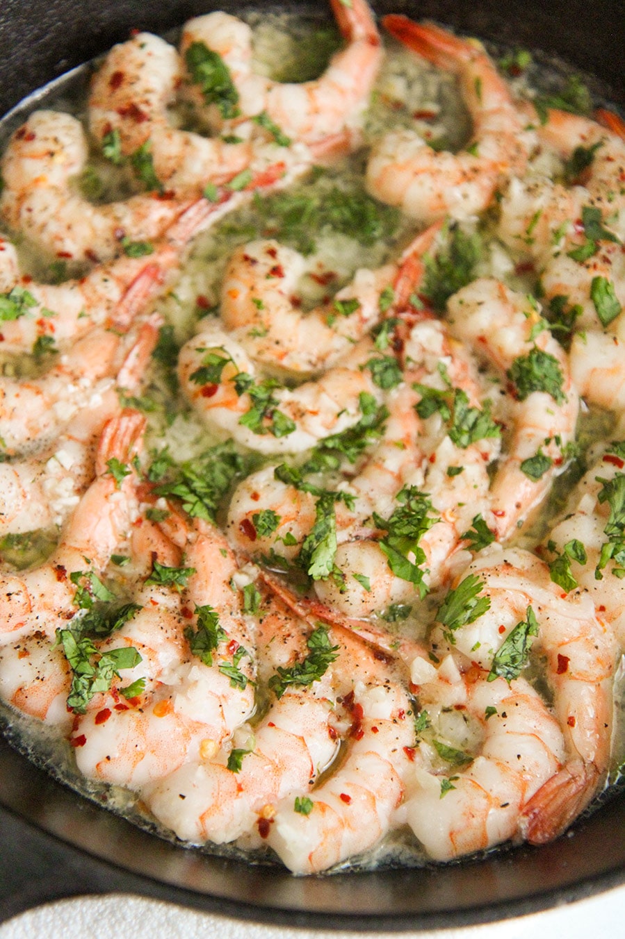 baked shrimp with parsley in a cast iron skillet up close. 