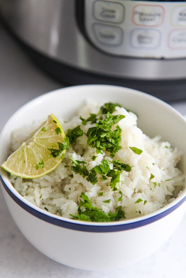 a blue and white bowl filled with fluffy rice, a lime wedge, and cilantro.
