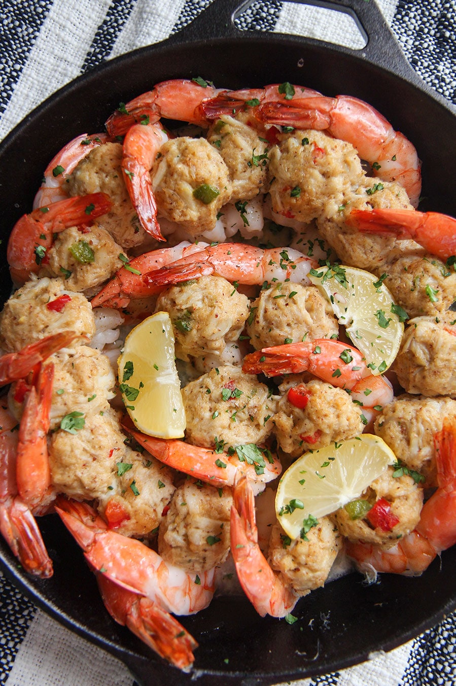 crab stuffed shrimp in a cast iron skillet with lemon wedges and parsley