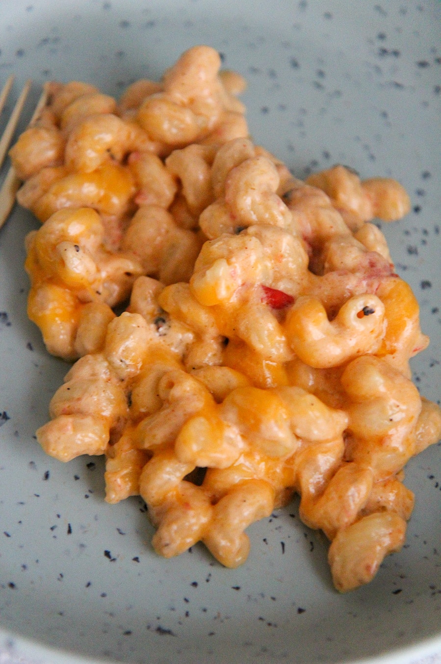 cheesy pasta on a blue plate up close. 