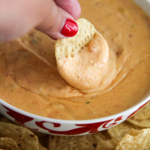 a chip dipped in a bowl of yellow queso.