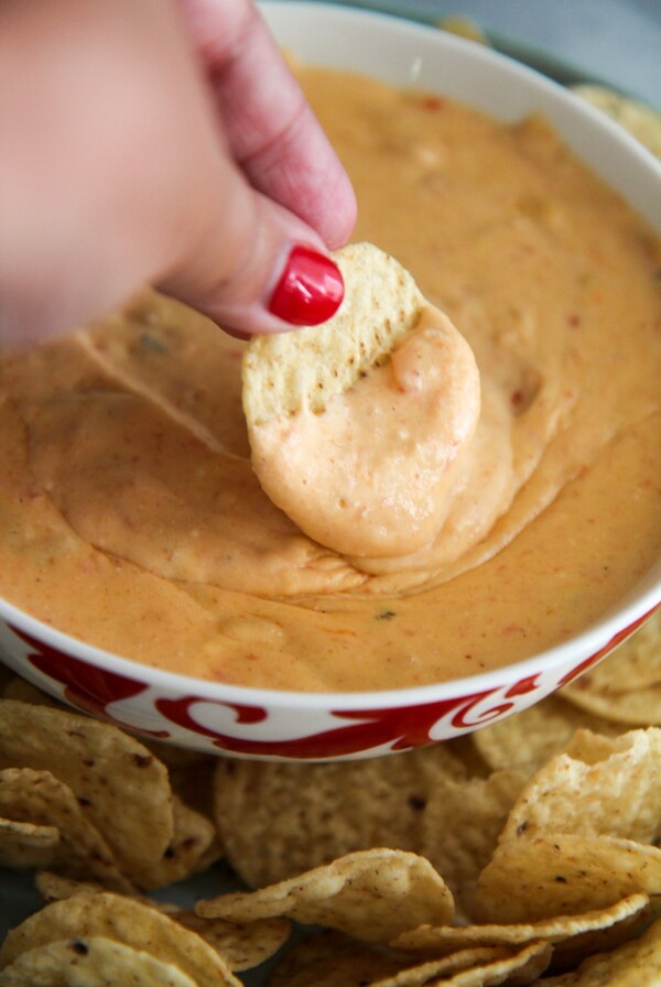a chip dipped in a bowl of yellow queso.