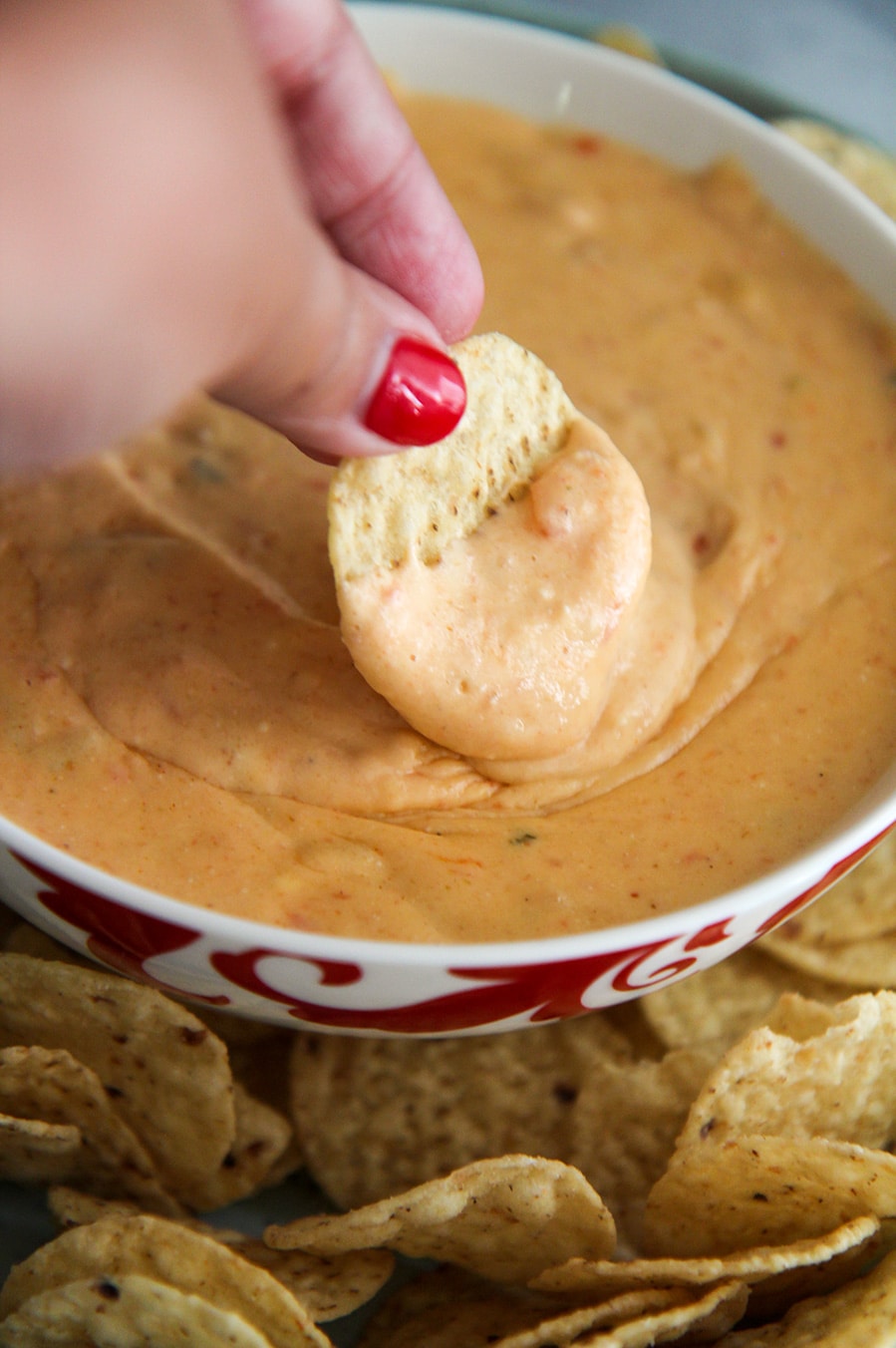 a chip dipped in a bowl of yellow queso.