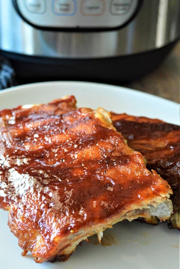 two racks of bbq ribs on a white plate up close.