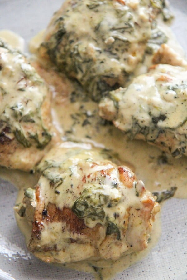 4 bone-in chicken thighs with spinach and cream on top.