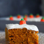 a slice of pumpkin cake with cream cheese frosting up close.