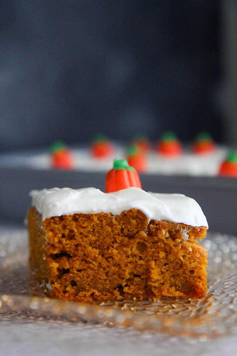 a slice of pumpkin cake with cream cheese frosting up close.