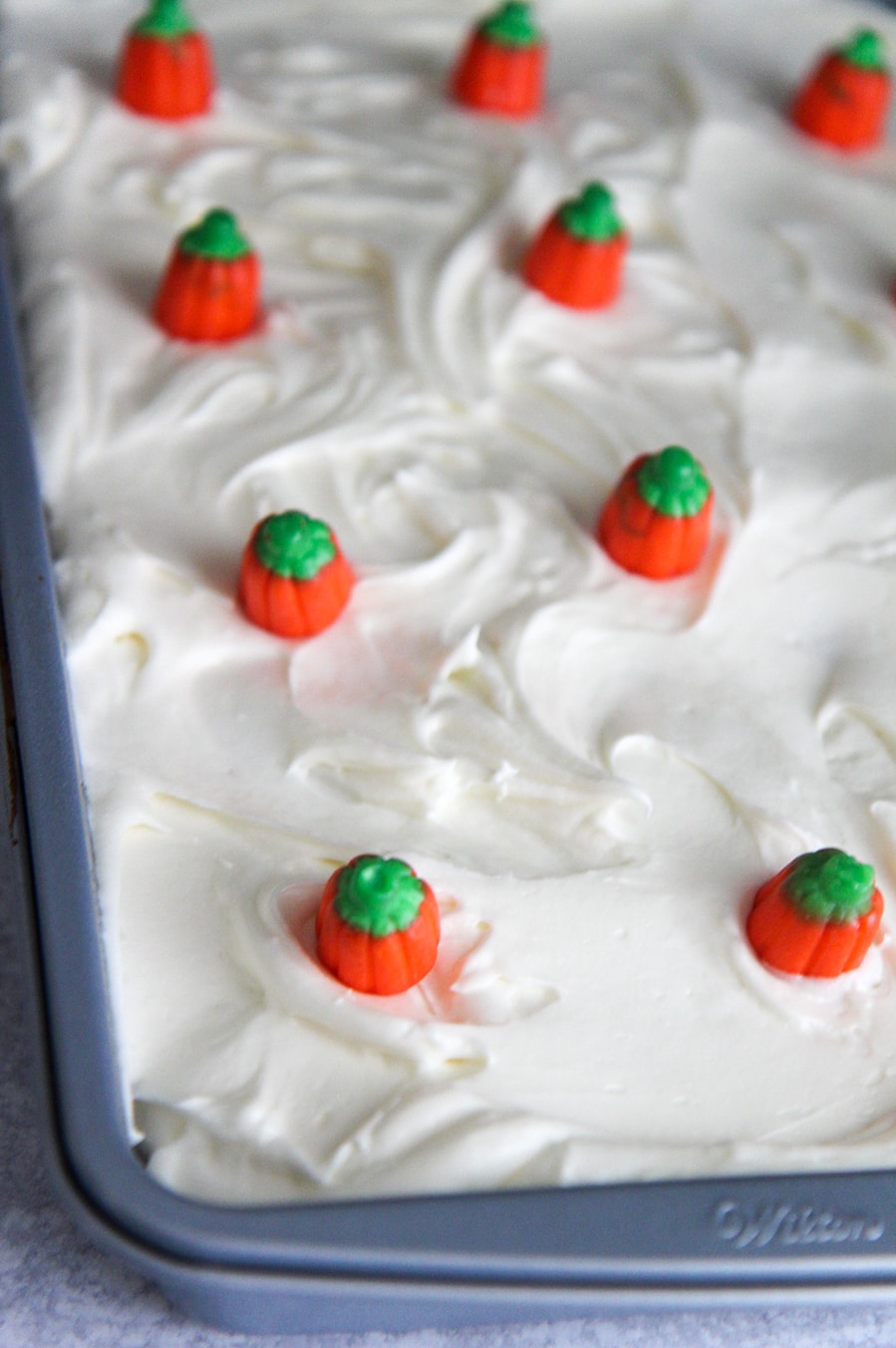 An entire cake in a 9x13 baking pan with frosting and pumpkin candies.