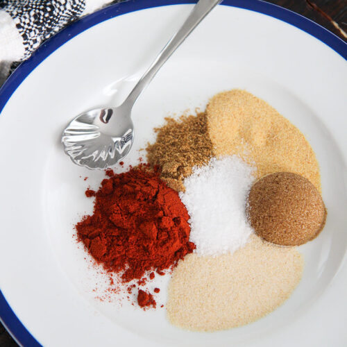 brown sugar and 5 spices on a white plate with a small spoon and towel on the side.