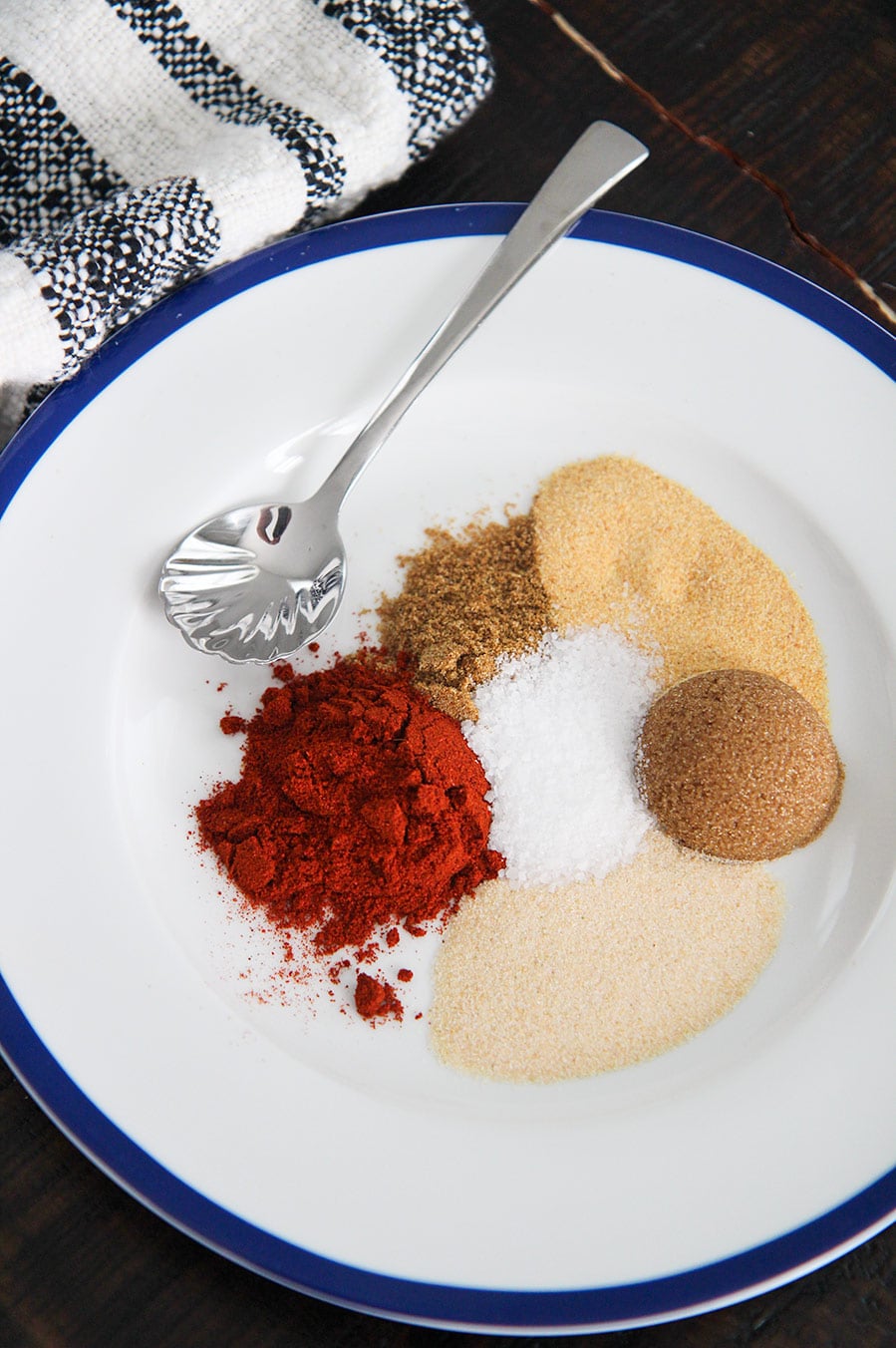 brown sugar and 5 spices on a white plate with a small spoon and towel on the side.