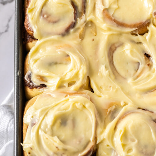 six jumbo cinnamon rolls with cream cheese frosting up close.