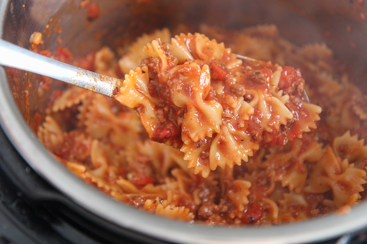 a spoonful of farfalle pasta with sauce up close. 