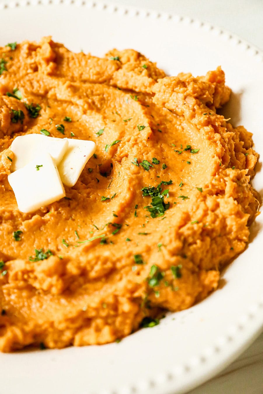 mashed sweet potatoes with butter and green herbs on top. 