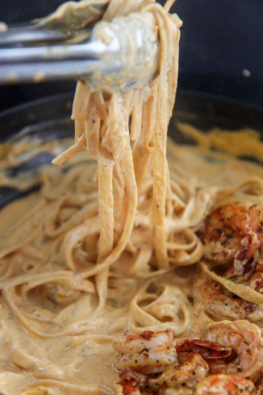 tongs holding a serving of pumpkin fettuccine alfredo