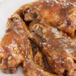 smothered wings on a white plate up close.