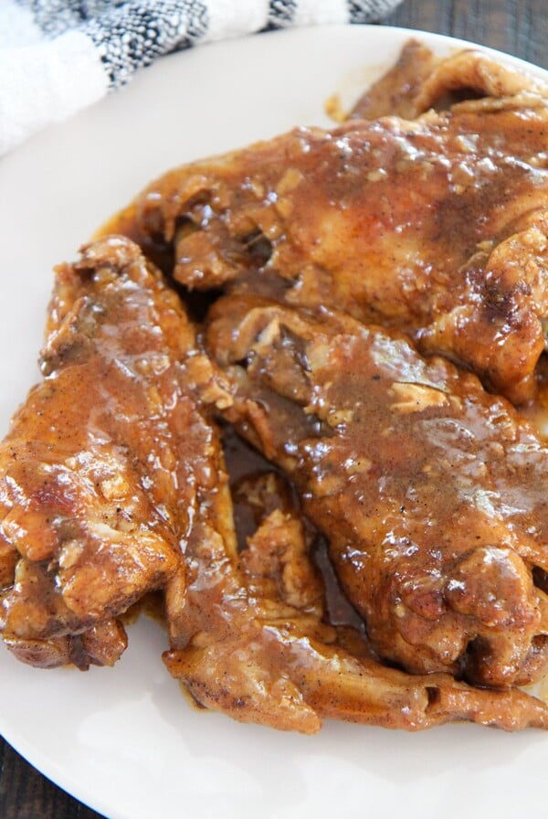 smothered wings on a white plate up close.